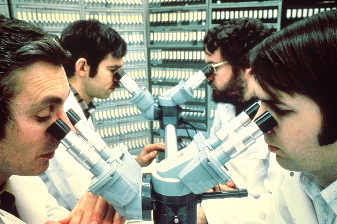 Two researchers working side by side at a microscope